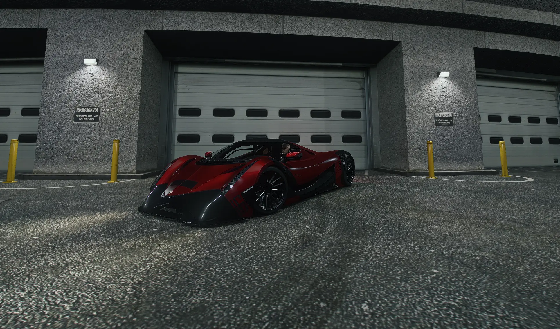 Red coupe parked at a roll-up door at night