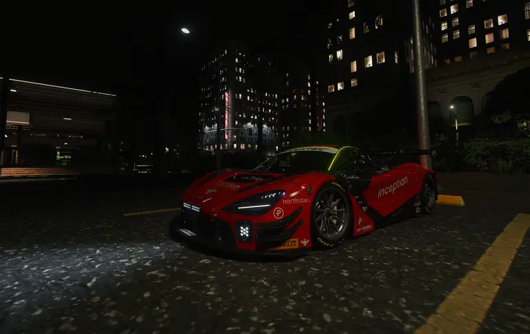 Red race car in full livery on a city street at night